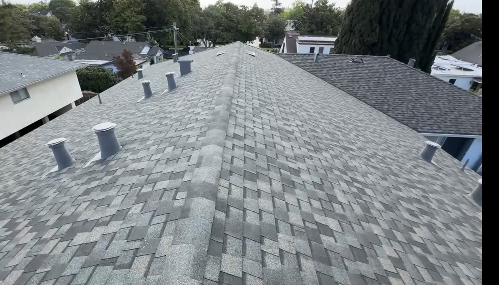Completed asphalt shingle roof with ridges, roof planes, and penetrations